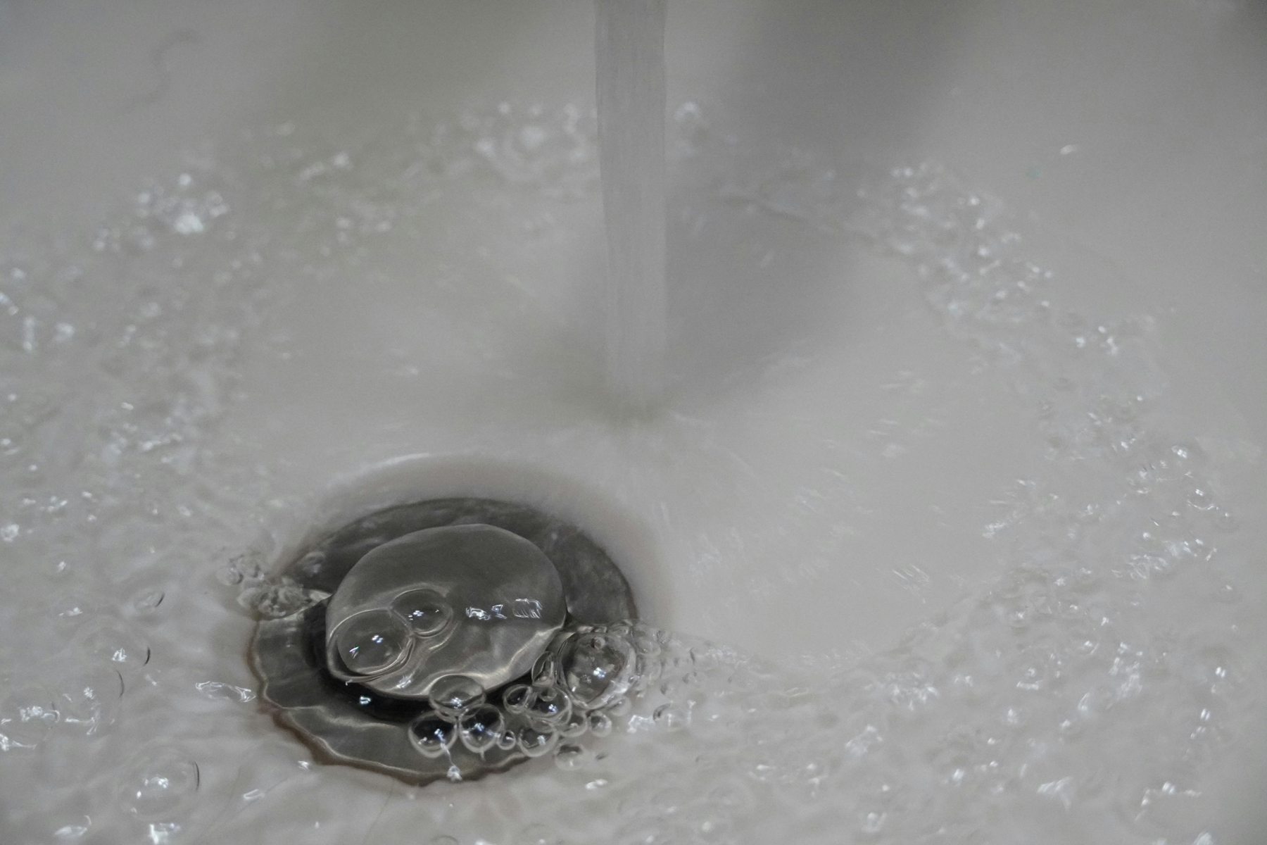 Wasser läuft gurgelnd in einen Küchenabfluss